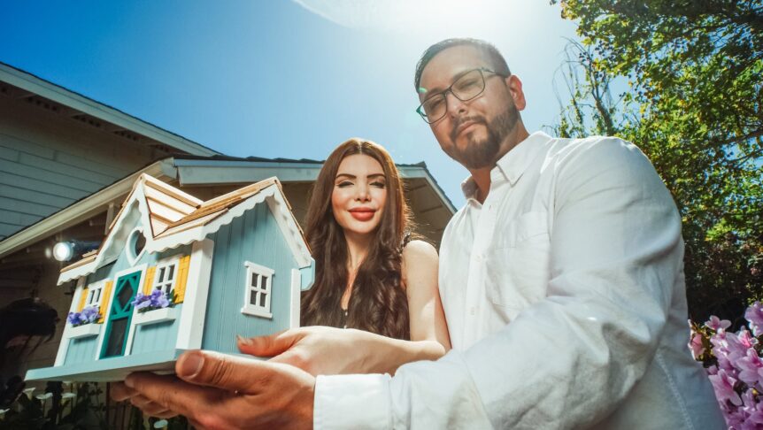 man and woman holding a miniature house
